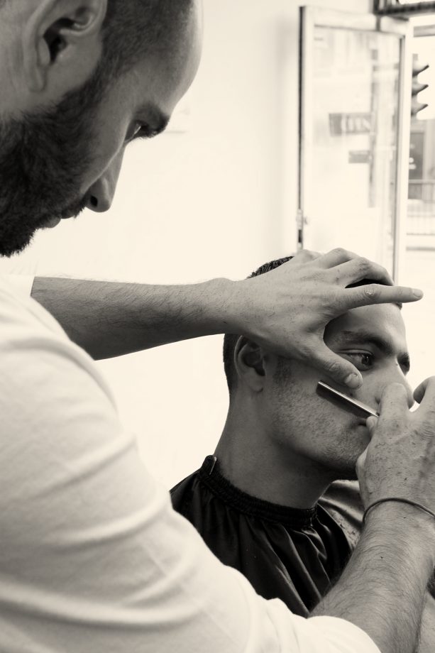 A barber lining up a beard with a straight razor